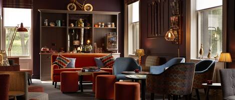 A cozy living room with a fireplace, comfortable seating, and a bookshelf filled with books and decorative items.