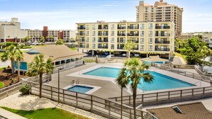 Un hotel con una amplia piscina al aire libre, varios balcones y vistas del entorno.