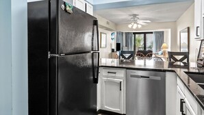 Una cocina moderna con refrigerador negro, lavavajillas de acero inoxidable y armarios blancos.