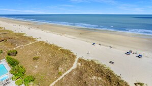 A beach with a clear view of the ocean, a sandy shoreline, and a pool area with a lifeguard tower. - Spacious, oceanfront family condo rental w/amazing views, pool, hot tubs in North Myrtle Beach (North Myrtle Beach)