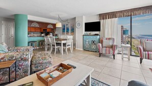 A spacious living area with a dining table, chairs, a sofa, and a balcony with a view. - Spacious, oceanfront family condo rental w/amazing views, pool, hot tubs in North Myrtle Beach (North Myrtle Beach)