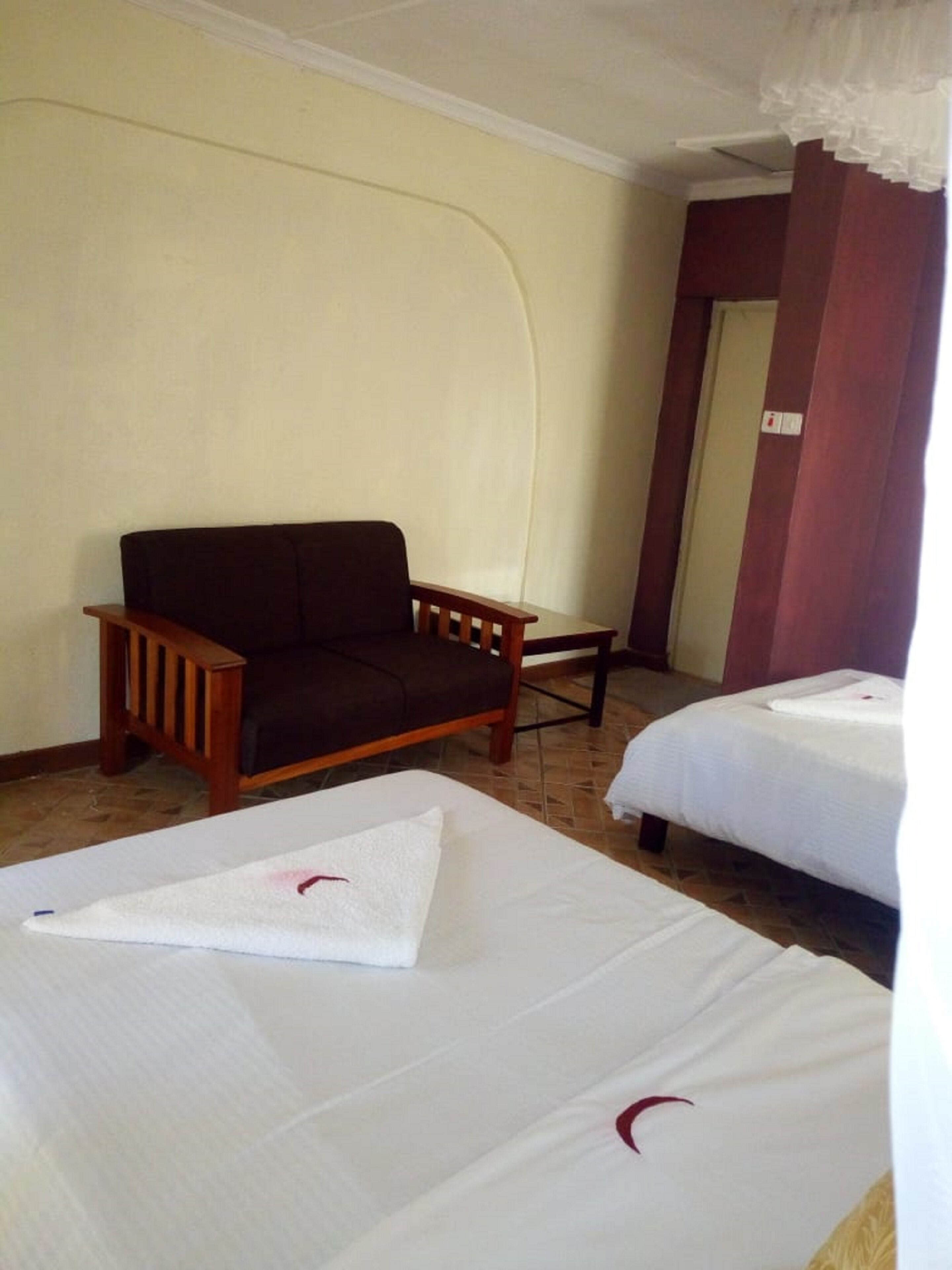 Habitación de hotel con sofá, dos camas y una puerta.