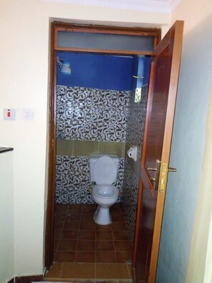 Un baño pequeño con inodoro, azulejos estampados y una pared azul.