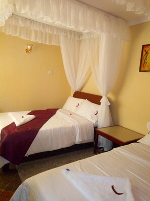 Una habitación de hotel con dos camas, una mesita de noche y un aplique de pared.