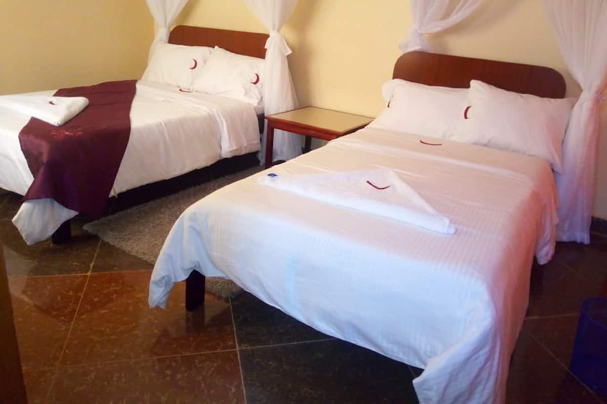 A hotel room with two beds, each with white bedding and red crescent moon pillows.
