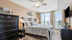 A bedroom with a bed, dresser, nightstands, a ceiling fan, and a view of the ocean through large windows. - Premier resort offering deluxe oceanfront condos in the heart of family-friendly North Myrtle Beach (North Myrtle Beach)
