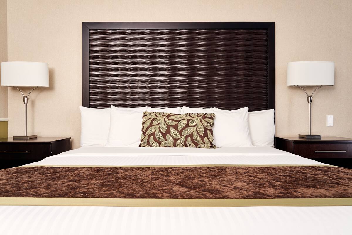A hotel room with a large bed, two bedside tables, and a headboard.