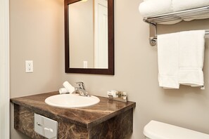 Une salle de bain avec un lavabo en marbre, un miroir, un porte-serviettes et des toilettes.