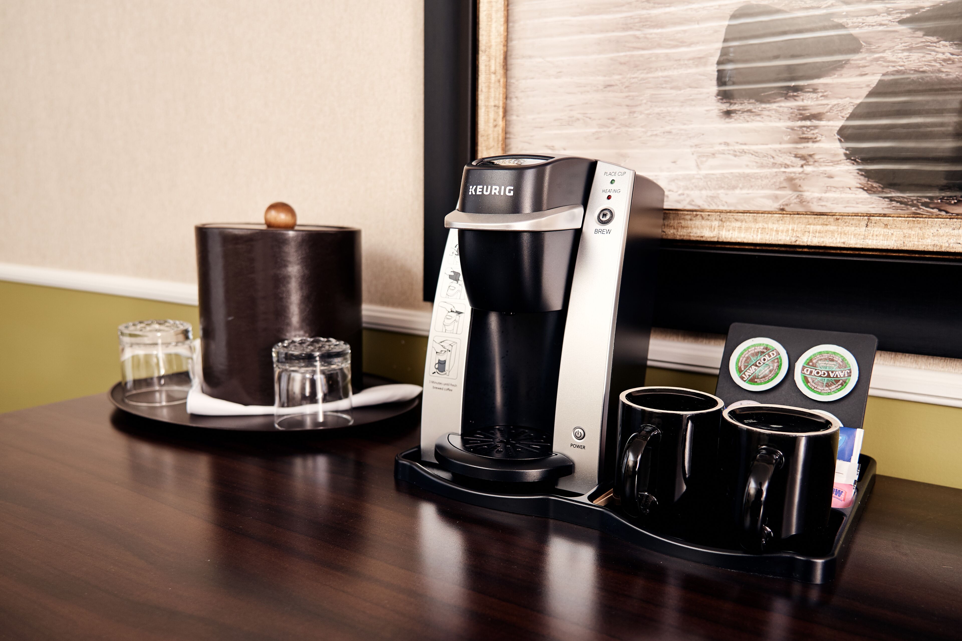 Una cafetera Keurig con dos tazas y un depósito de agua sobre una mesa de madera.