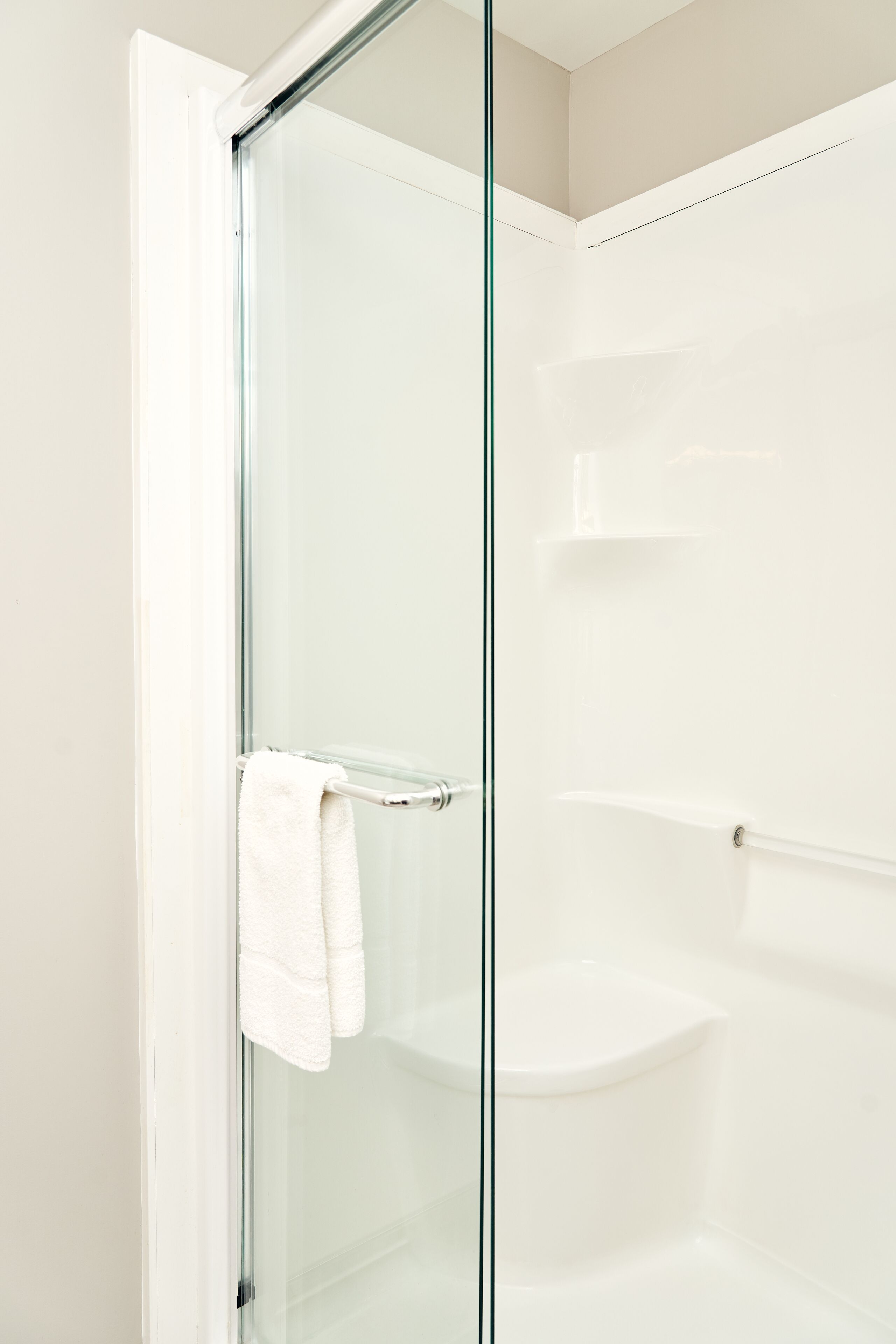 A glass-enclosed shower with a white towel on a metal towel bar.