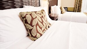 A hotel room with a neatly made bed, a headboard, a bedside table, and a lamp. - RiverRock Inn & Conference Centre (Clarence-Rockland)