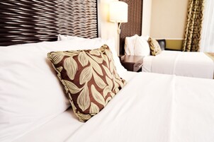 Quarto de hotel com cama bem arrumada, cabeceira, mesa de cabeceira e abajur.