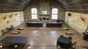 An indoor recreational area with a ping pong table, seating, and a stone fireplace. - Circle M Lodge is The Perfect Get-A-Way (Stratford)