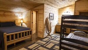 A wooden cabin bedroom with two bunk beds, a wooden wardrobe, a mirror, and a lamp. - Circle M Lodge is The Perfect Get-A-Way (Stratford)