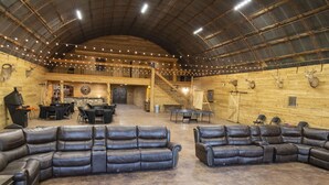 A spacious indoor area with leather sofas, a ping pong table, and a staircase leading to an upper level. - Circle M Lodge is The Perfect Get-A-Way (Stratford)