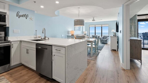 A modern kitchen with a built-in dishwasher, a dining area with a view, and a living room with a ceiling fan. - Discover Comfort & Convenience (North Myrtle Beach)