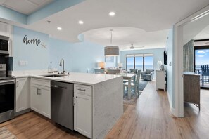 A modern kitchen with a built-in dishwasher, a dining area with a view, and a living room with a ceiling fan.