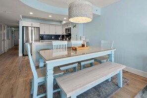 A modern kitchen with white cabinets, a stainless steel refrigerator, and a hanging light fixture.