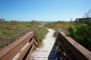A wooden boardwalk leading to a beach with dunes and a clear sky. - Discover Comfort & Convenience (North Myrtle Beach)