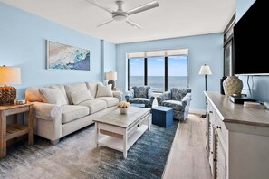 A living room with a sofa, armchairs, a coffee table, and a view of the ocean.