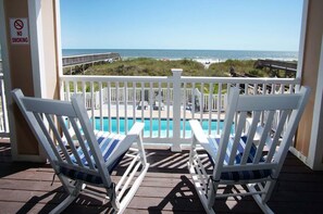 A poolside view with two white lounge chairs, a no-smoking sign, and a view of the ocean. - Discover Comfort & Convenience (North Myrtle Beach)