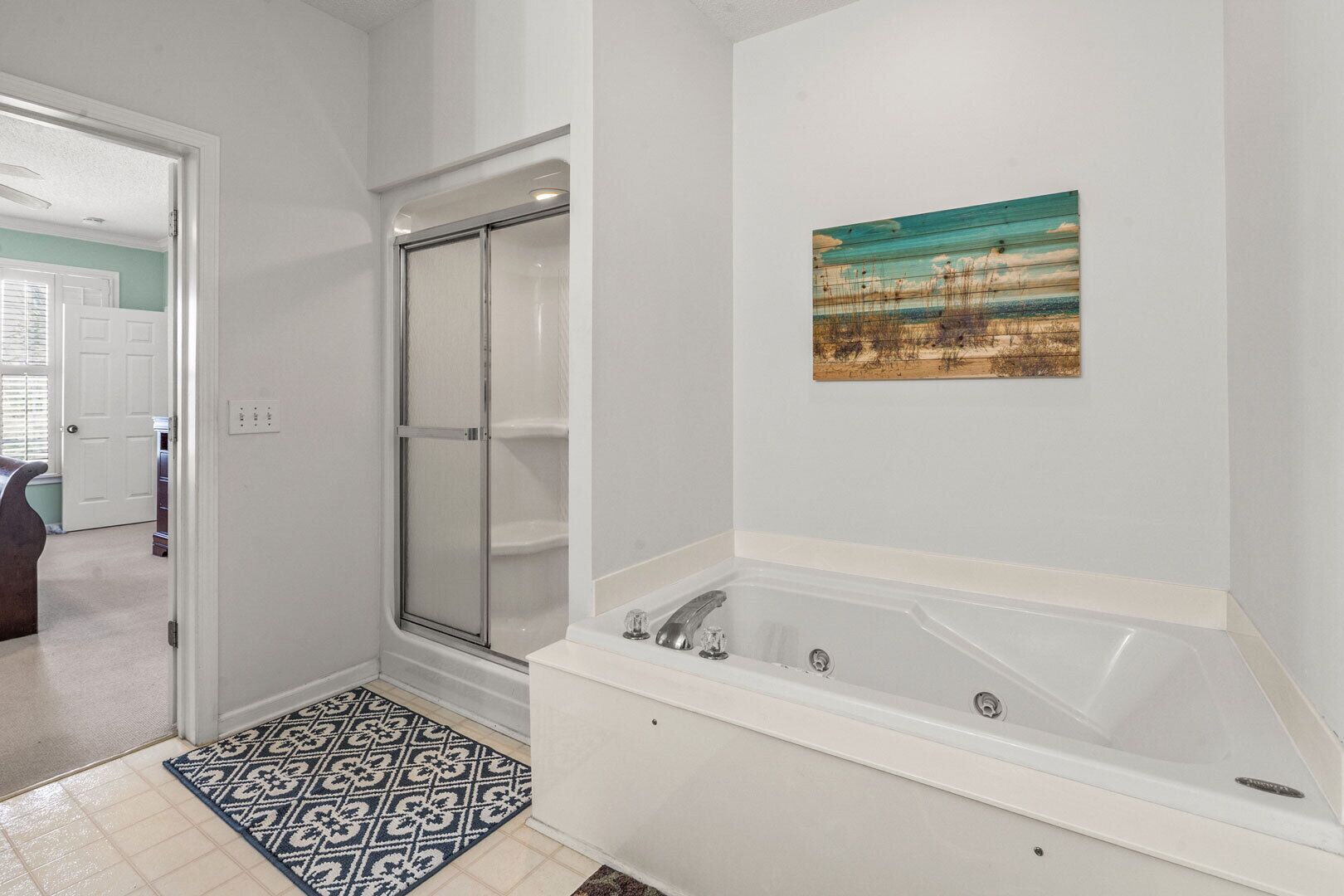 Un baño con ducha a nivel del suelo, bañera y puerta que da a un pasillo.