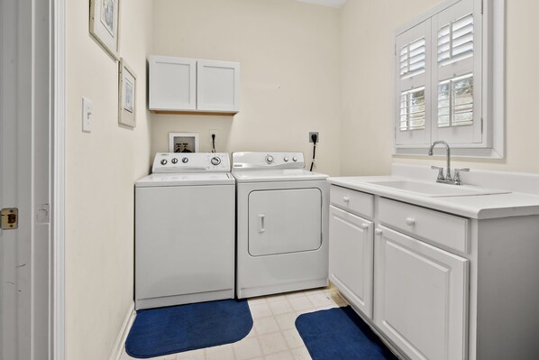 A laundry room with a washer and dryer, a sink, and a window with blinds. - Spacious, family-friendly oasis in North Myrtle Beach (North Myrtle Beach)