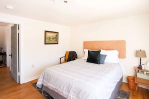 A bedroom with a bed, a nightstand, a lamp, and a painting on the wall.