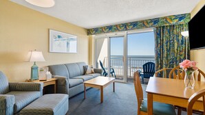 Habitación de hotel con balcón, sofá, mesa y una silla.