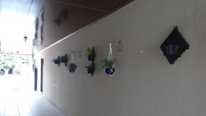 A corridor with tiled flooring and walls adorned with hanging planters. - Hotel Mapara Beach (Baiao)