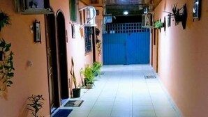 A corridor with tiled flooring, potted plants, and wall-mounted decorations. - Hotel Mapara Beach (Baiao)
