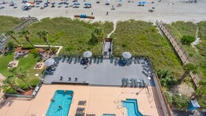 Ein Poolbereich auf dem Dach mit mehreren Pools, Liegestühlen und Sonnenschirmen.