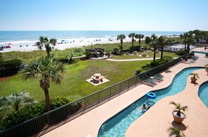 A pool area with a view of the beach, palm trees, and lounge chairs. - Luxury oceanfront resort-workout room, indoor/outdoor pools, lazy river, kids' pool-in Ocean Drive (North Myrtle Beach)