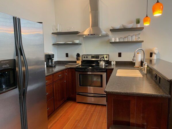 A modern kitchen with stainless steel appliances, wooden cabinets, and a granite countertop. - Beautiful center of Kalispell apartment (Kalispell)