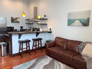Enjoy a compact yet functional space with a kitchenette, dining area, and cozy living space featuring a leather sofa.