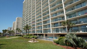 Un hotel de varios pisos con balcones, piscina y un césped cuidado.