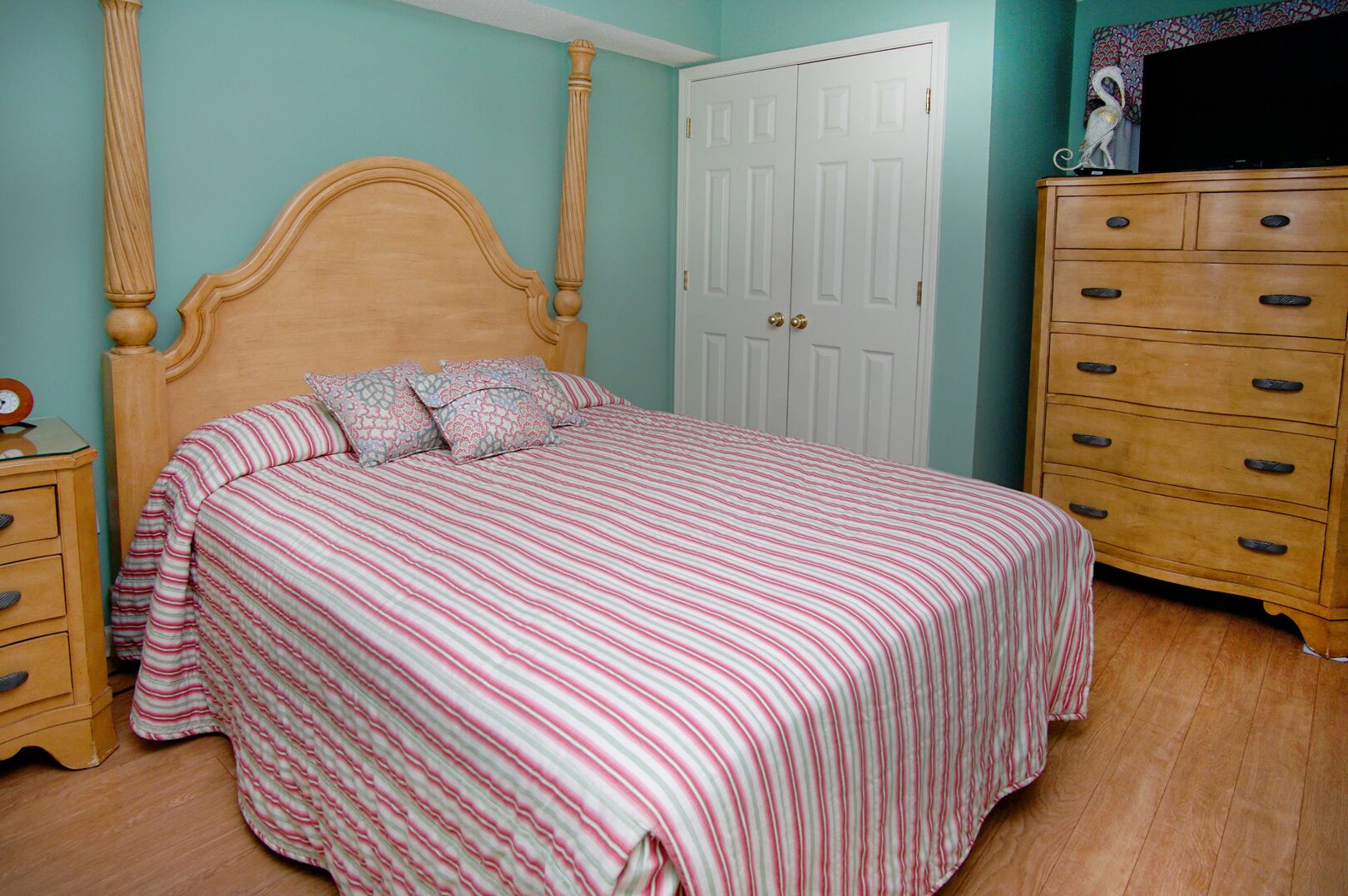 A bedroom with a bed, a dresser, and a door.