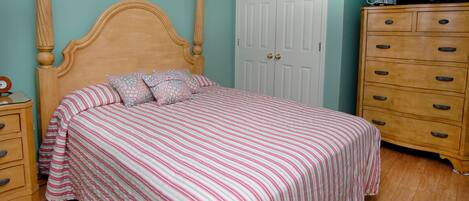 A bedroom with a bed, a dresser, and a door.