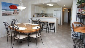 Un comedor con una mesa redonda, seis sillas y una cocina al fondo.