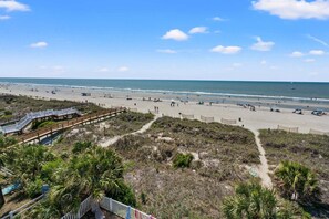 A beach with a wooden boardwalk leading to the shore, sandy beach, and ocean.