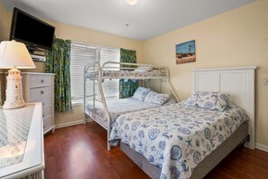 A bunk bed room with a television, a lamp, and a painting on the wall.