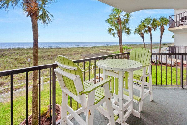A balcony with a view of the ocean, featuring a table and two chairs.