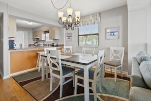 A modern kitchen with white cabinets, a wooden island, and a dining area with a table and chairs.