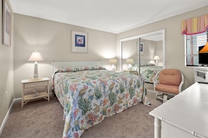A bedroom with a bed, bedside tables, a chair, a desk, and a mirror.
