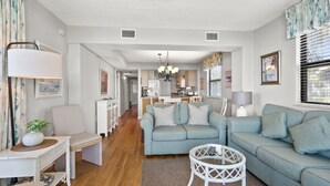Un salon moderne avec un canapé, une table basse et, au fond, un coin repas.