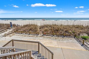 A beach view with wooden walkways and a concrete path leading to the shore. - Gorgeous family ready oceanfront duplex, beautifully decorated, spacious oceanfront decks (North Myrtle Beach)