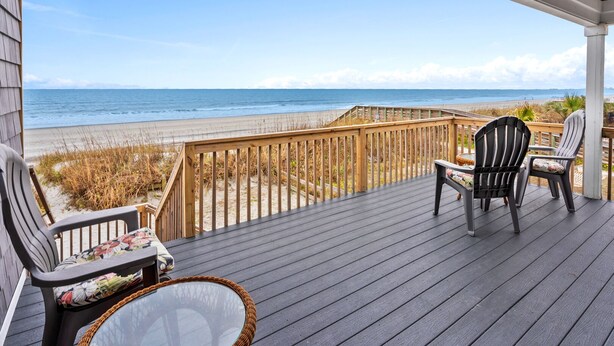 Une terrasse en bois offrant une vue sur la plage et l’océan.