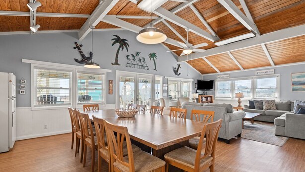 A spacious living area with a large wooden dining table, comfortable seating, and a high ceiling with exposed beams. - Beautiful décor & large private pool! Spacious family home includes decks & huge yard in N. Myrtle. (North Myrtle Beach)