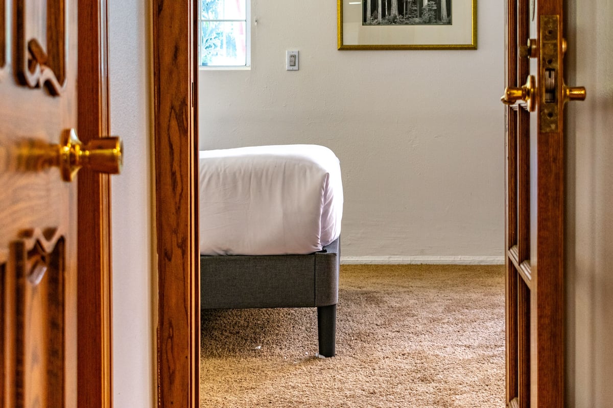 Ein Schlafzimmer mit einem Bett, einem Fenster und einem gerahmten Bild an der Wand.