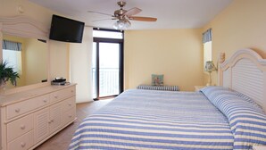 Una camera da letto con un letto, una cassettiera, una televisione, una ventola a soffitto e una finestra con vista.
